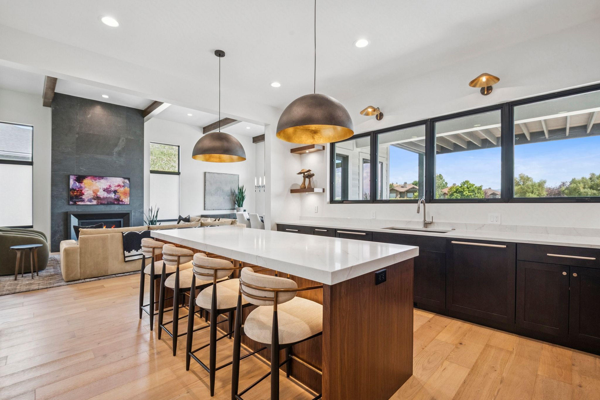 Spacious kitchen featuring a large island walnut cabinetry, and light hardwood flooring, designer lighting, with Wolf and Subzero appliances.