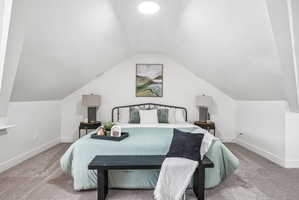 Room featuring an angled ceiling and neutral-toned carpeting