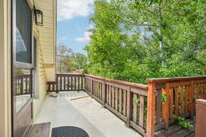 Exterior balcony featuring a wood railing and mature tree canopy