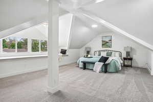 Carpeted room featuring a window seat, sloped ceilings with exposed beams, and a round ceiling light fixture