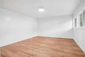 Spacious room featuring wood-finish flooring, white walls, and bright white trim
