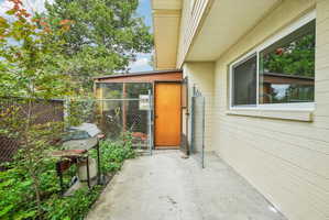 Concrete patio with a chain link fence, an exterior wall with horizontal siding, and a sliding window