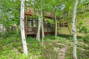 Exterior featuring a two-story wood deck, screened porch, and yellow horizontal siding