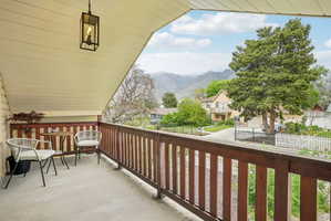 Covered balcony with wood railing, concrete flooring, and a black lantern-style pendant light