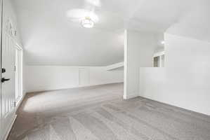 Expansive carpeted area featuring a white door with a window, white walls, and a contemporary flush mount light fixture