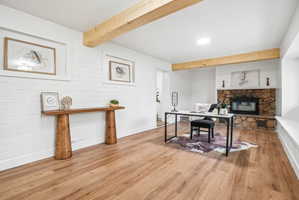 Spacious interior featuring wood-finish flooring, exposed ceiling beams, and a stone-faced fireplace with an integrated hearth