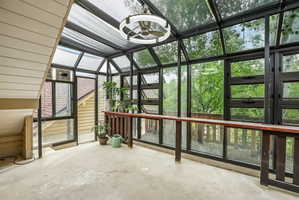 Sunroom featuring a full glass ceiling, expansive windows, a ceiling fan fixture, and a built-in wooden counter with a railing