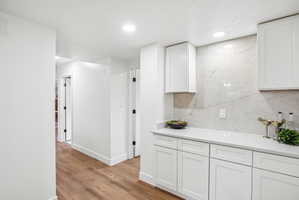 Built-in white cabinetry with a light-colored countertop and a large-format tile backsplash