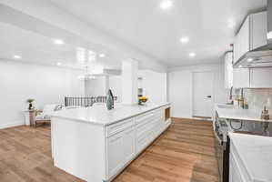 Spacious kitchen presenting a large central island with white cabinetry and light-toned countertops