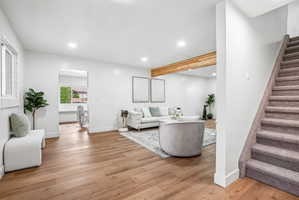 Spacious living area featuring wood-finish flooring, recessed lighting, and a prominent wood beam accent