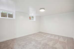 Room featuring light gray patterned carpeting, white painted walls, white baseboards, and two windows