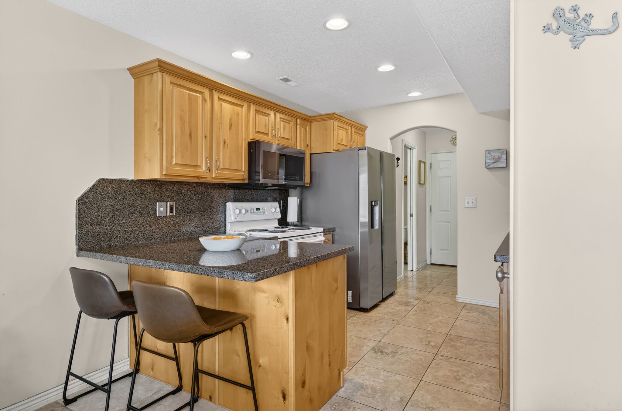 Kitchen featuring arched walkways, a kitchen bar, decorative backsplash, white range with electric stovetop, and a peninsula