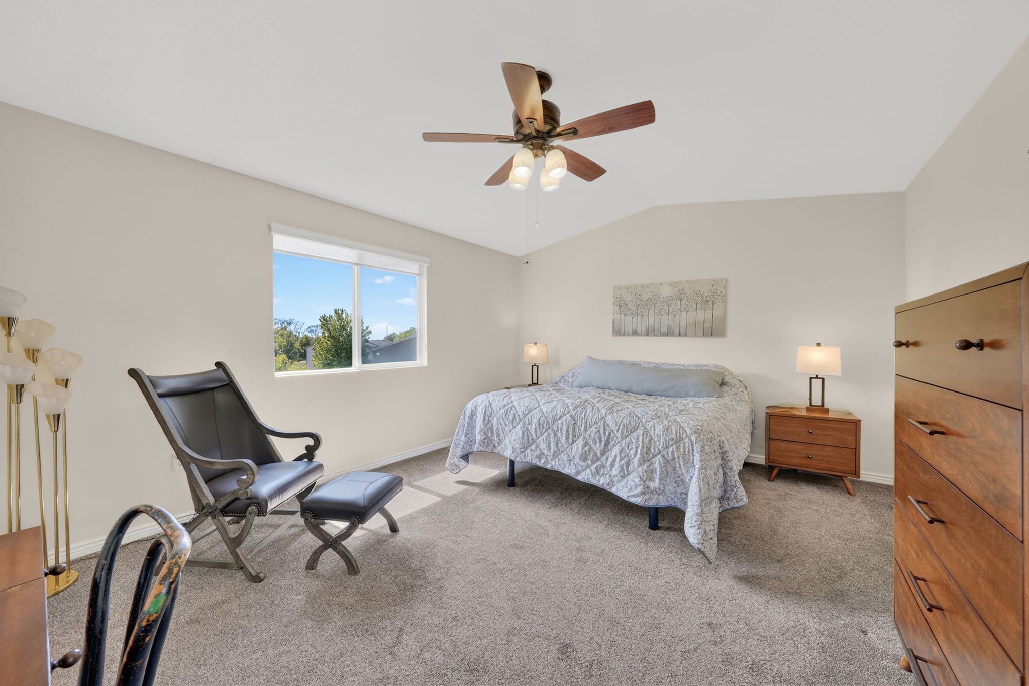 Carpeted bedroom featuring ceiling fan and vaulted ceiling