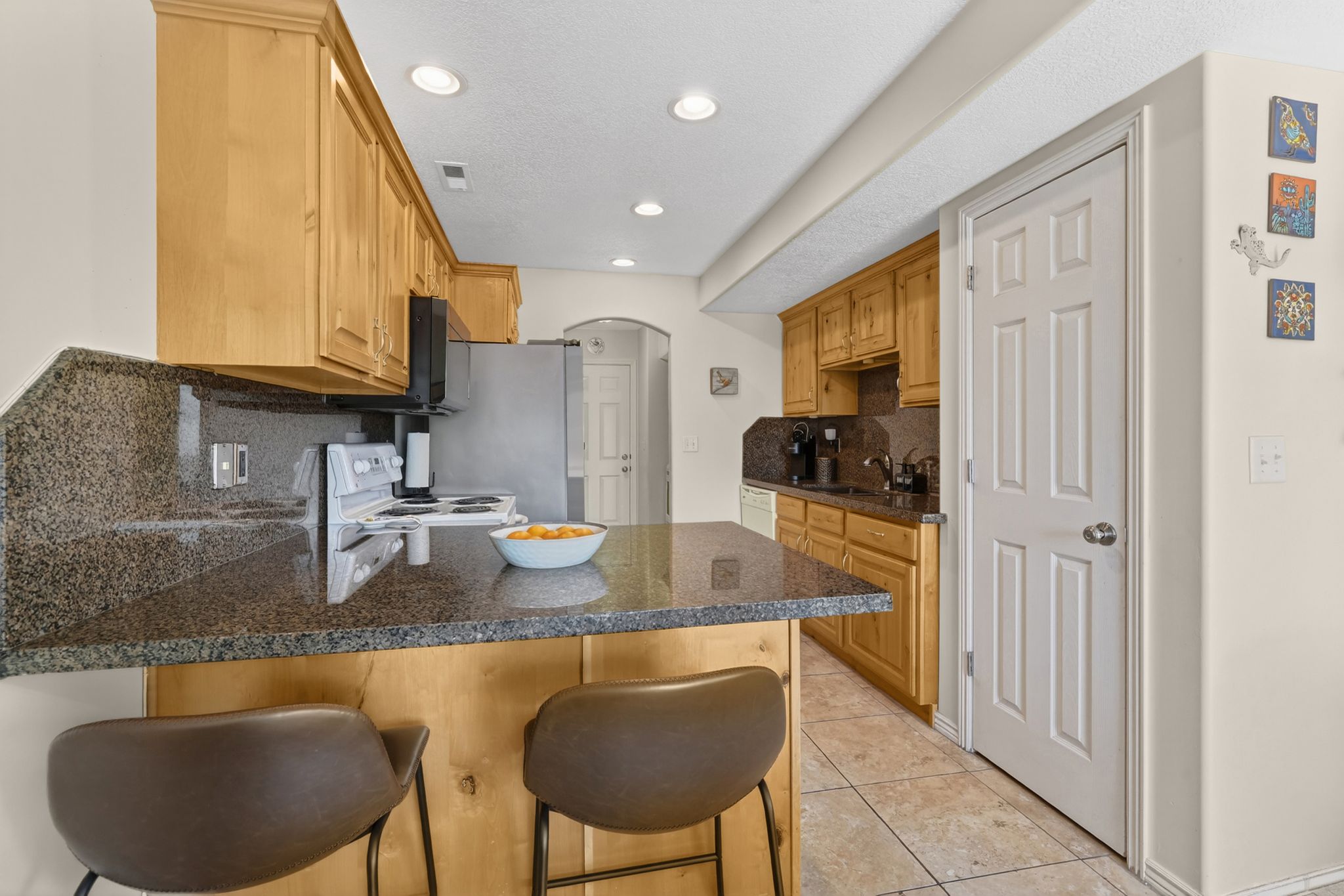 Kitchen with arched walkways, a peninsula, a breakfast bar, tasteful backsplash, and light tile patterned floors