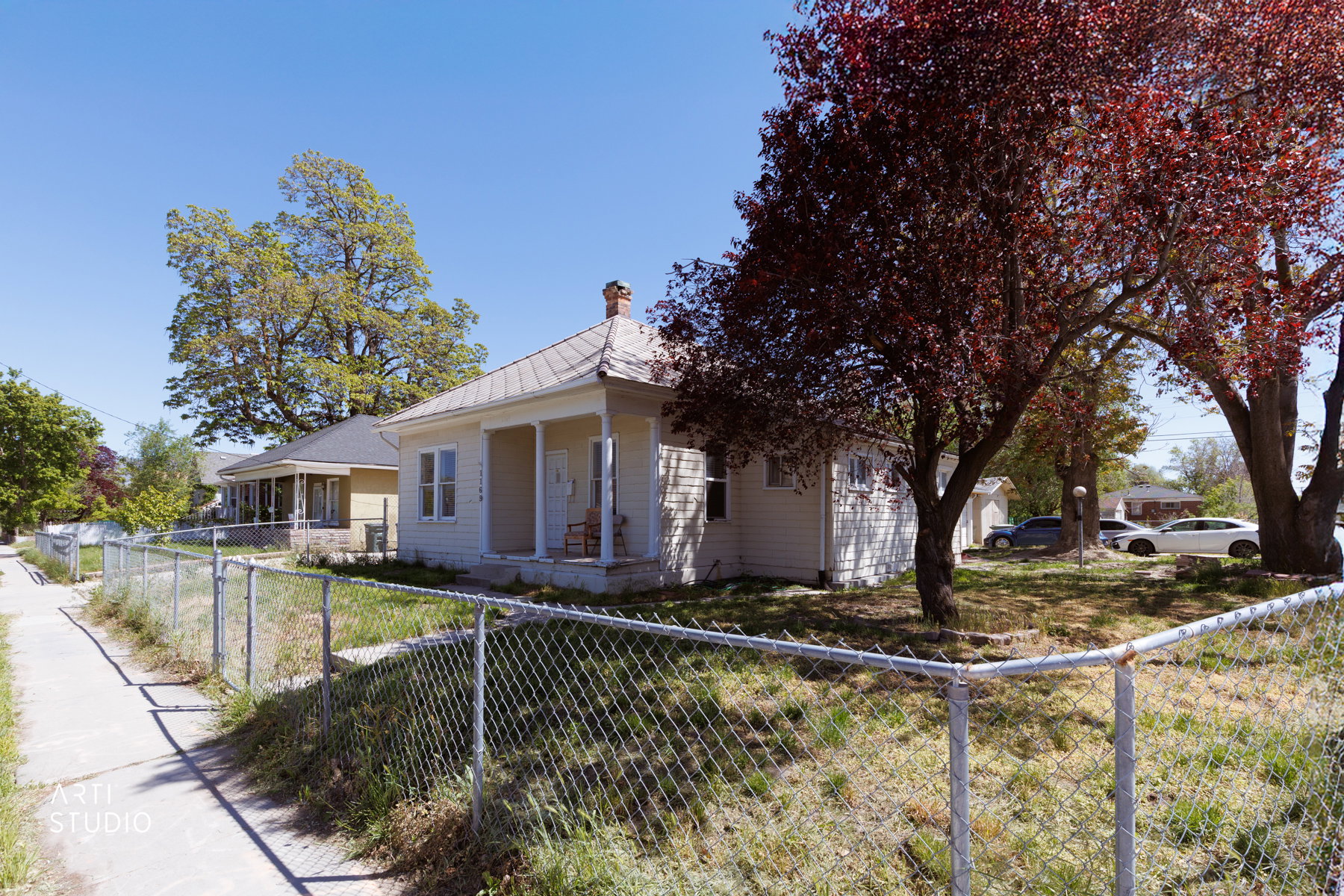 Single-story residence featuring a covered front porch with white columns, a pitched roof, and an exposed brick chimney