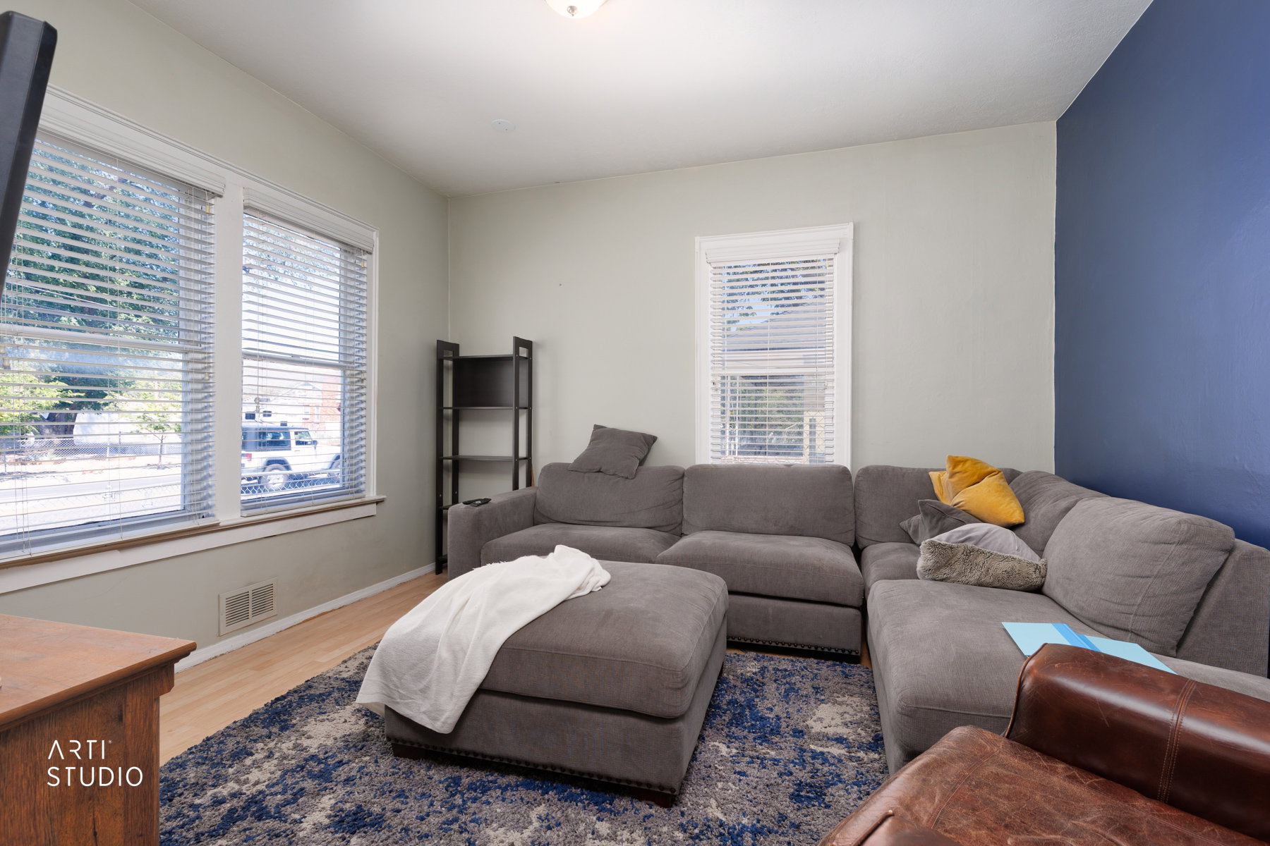 Light-filled interior featuring wood-finish flooring, multiple windows with blinds, and a contrasting accent wall
