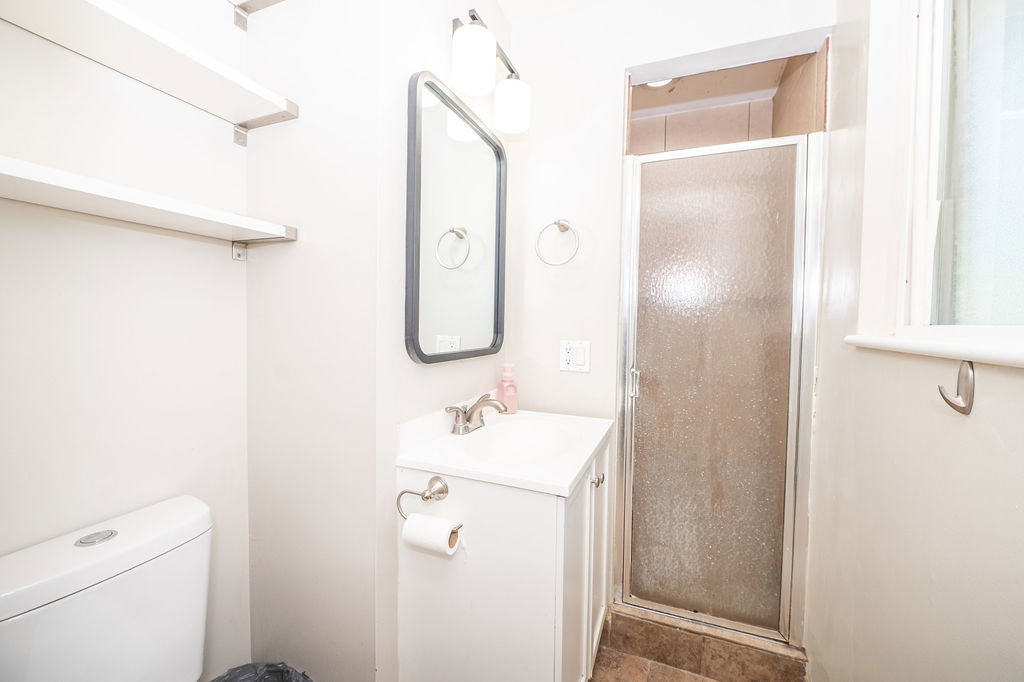 Bathroom featuring a rectangular framed mirror, vanity with an integrated sink, and a glass-enclosed shower