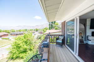 Exterior balcony featuring composite decking, wooden railing with post caps, and a white aluminum sliding glass door