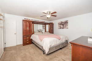Carpeted bedroom featuring a ceiling fan with integrated lighting, white walls, and a solid white door