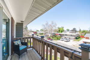 Outdoor balcony featuring wood-finish decking and a robust wood railing