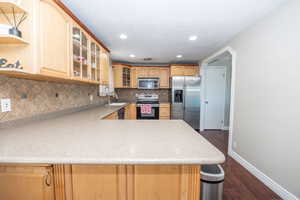 Kitchen featuring light wood cabinetry, a tiled backsplash, and stainless steel appliances