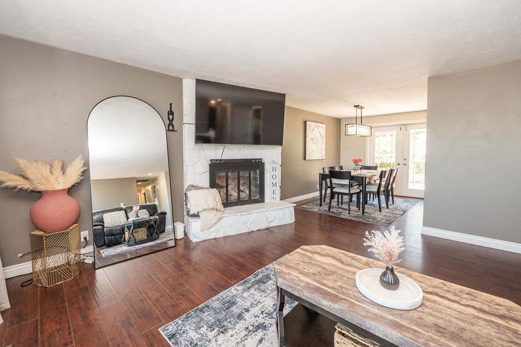 Spacious living area featuring rich wood-finish flooring and a stone-clad fireplace