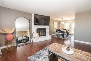Spacious living area featuring rich wood-finish flooring and a stone-clad fireplace