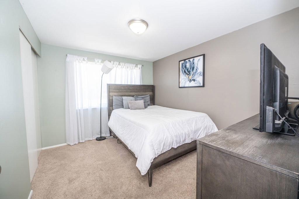 Carpeted room with a ceiling-mounted light fixture, light green and beige wall finishes, and a window with white sheer curtains