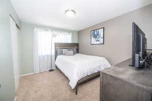 Carpeted room with a ceiling-mounted light fixture, light green and beige wall finishes, and a window with white sheer curtains