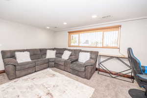 Recessed ceiling lighting illuminates a carpeted interior space with a window featuring wood-look blinds