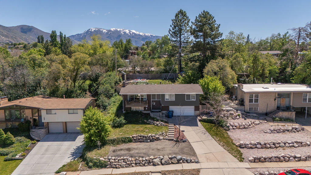 Split-level residence featuring a two-car garage, mature landscaping, and a concrete driveway