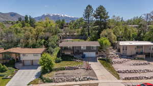 Split-level residence featuring a two-car garage, mature landscaping, and a concrete driveway