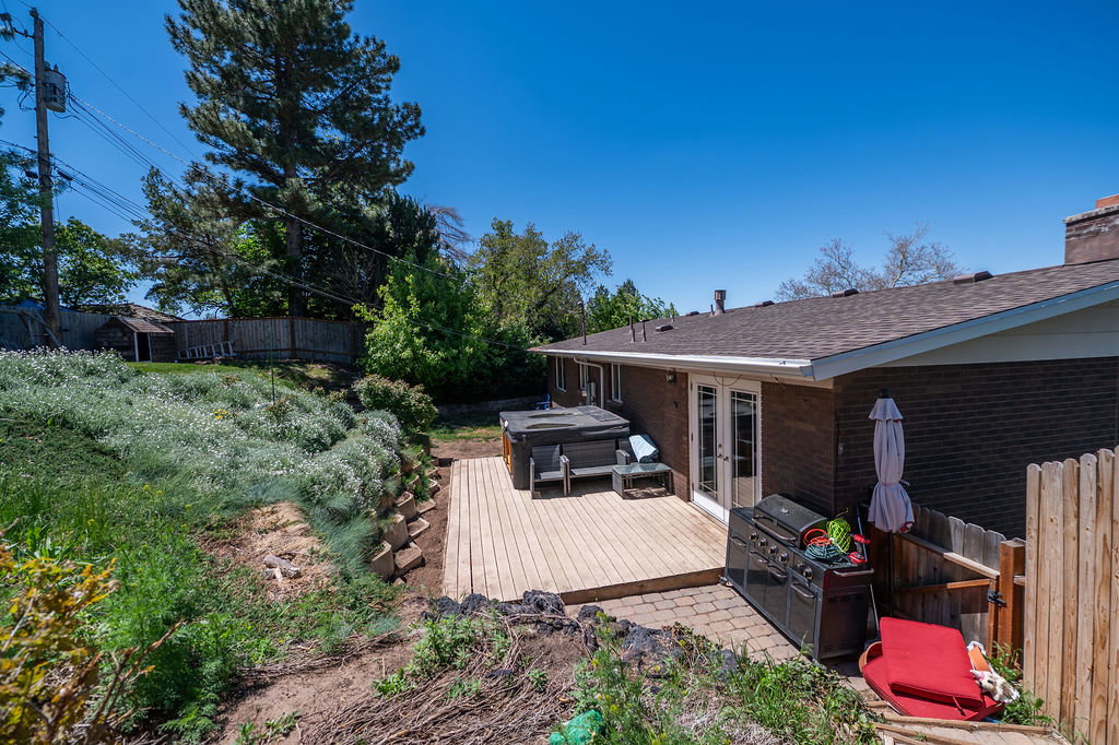 Exterior brick facade with a new roof, featuring a wood deck, double French doors, and a built-in outdoor spa