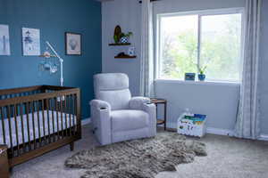 Window-lined room featuring a contrasting accent wall, neutral carpeting, and built-in shelving