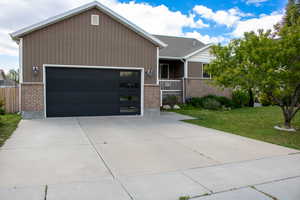 Contemporary exterior featuring a modern black garage door with frosted window panels, brown vertical siding, and a brick facade