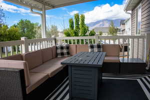 Covered outdoor deck featuring white railings and a mountain backdrop
