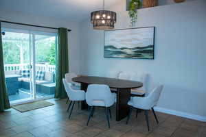 Dining area featuring tile flooring, a multi-tiered chandelier, and direct access to an outdoor deck through sliding glass doors