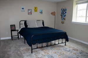 Carpeted room featuring a window with white trim, light-toned walls, and white baseboards