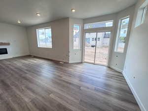 Spacious interior featuring wood-finish flooring, a contemporary fireplace with a wood mantle, and recessed lighting