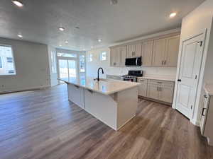 Modern kitchen featuring a central island with a quartz countertop and black gooseneck faucet
