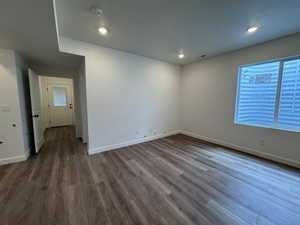 Spacious interior with wood-finish flooring, recessed lighting, white walls, and a prominent egress window