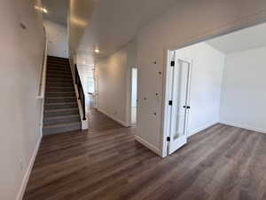 Inviting entry foyer featuring wood-finish flooring, a carpeted staircase with a black metal handrail, a white interior door with frosted glass paneling and black hardware, and recessed lighting