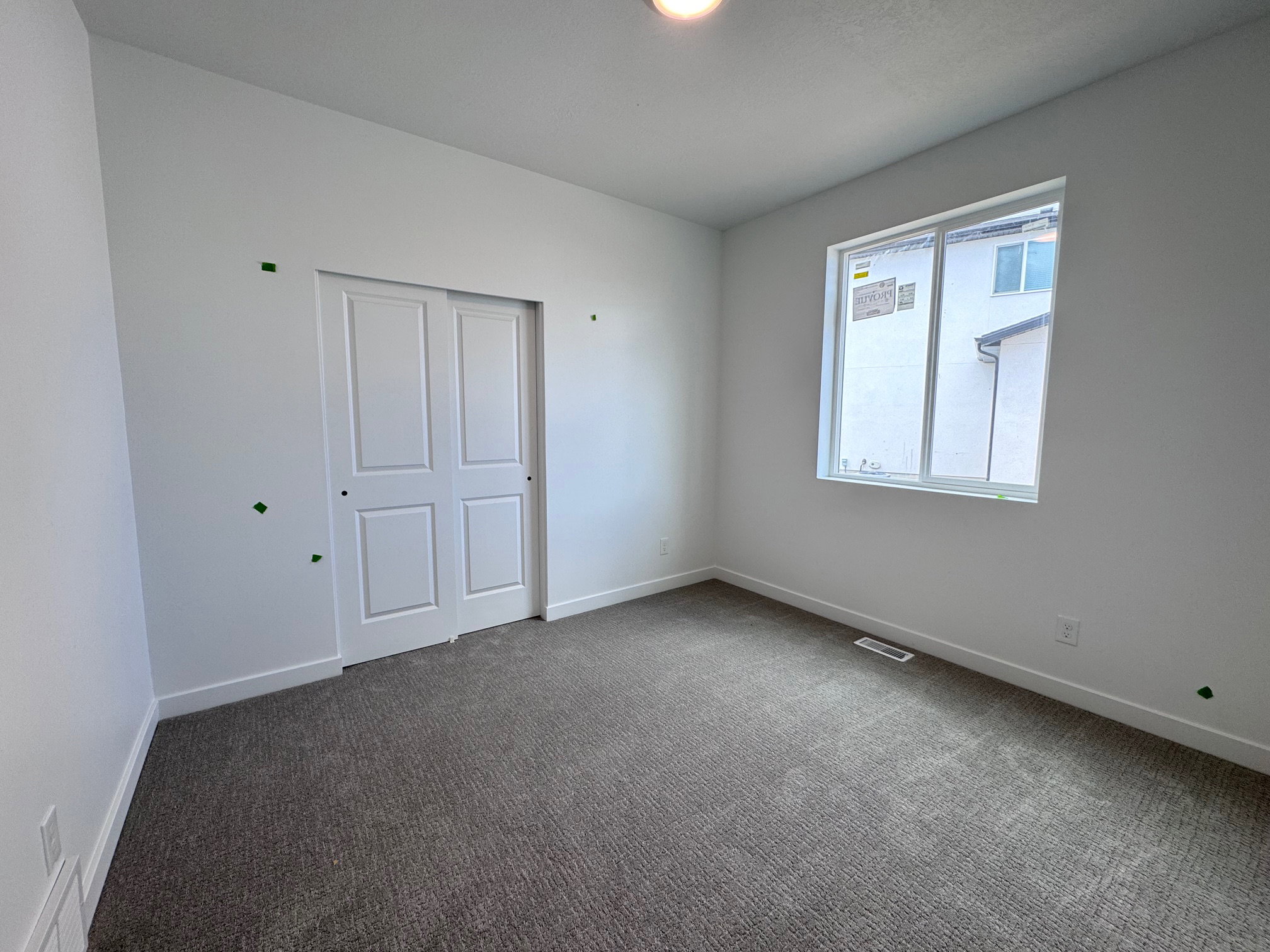 Neutral tone wall finishes with plush carpet flooring, a multi-pane window, and white bi-fold closet doors