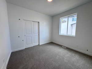 Neutral tone wall finishes with plush carpet flooring, a multi-pane window, and white bi-fold closet doors