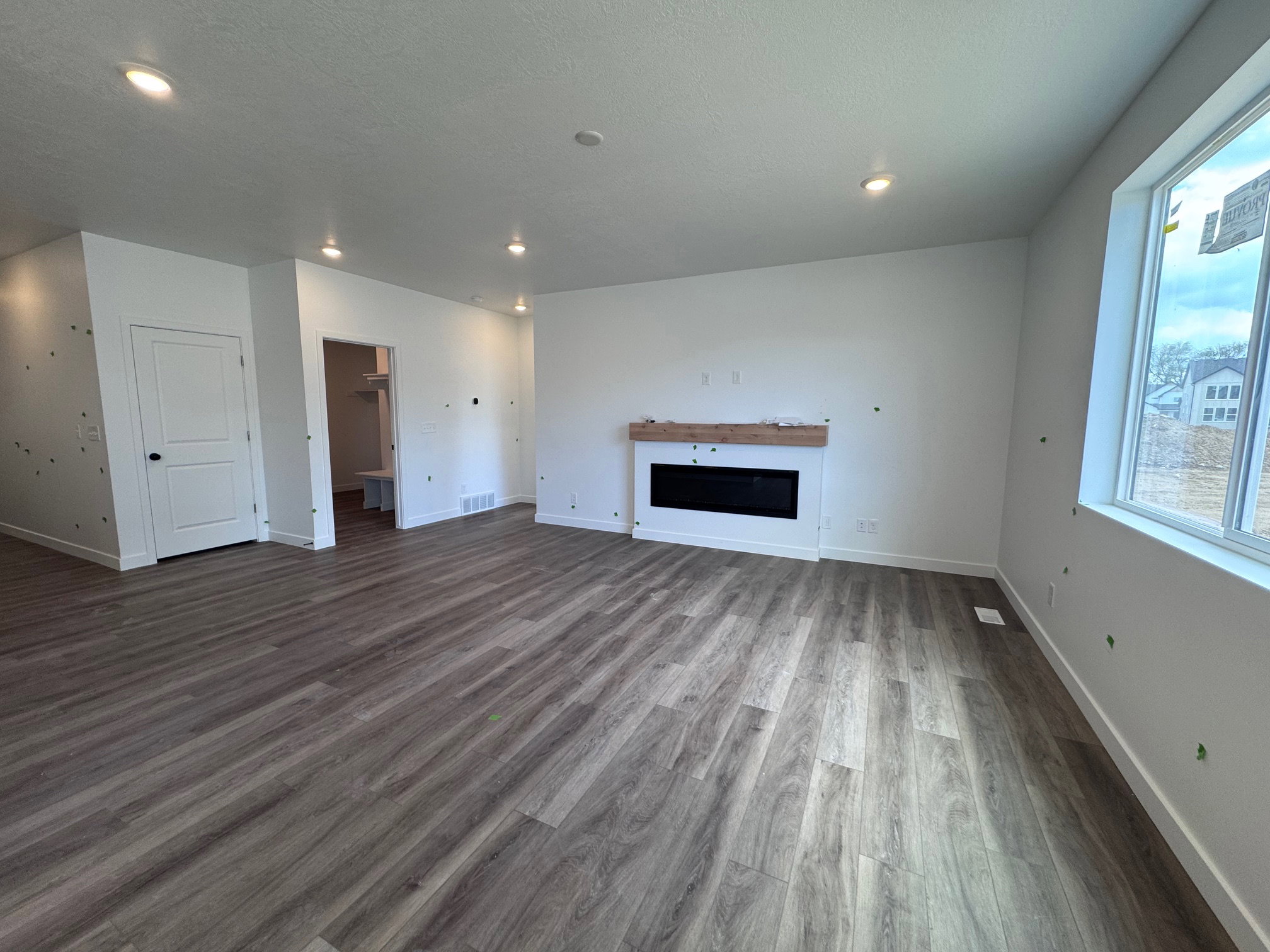 Spacious living area featuring wood-finish flooring, recessed lighting, and a modern built-in electric fireplace with a wood mantle