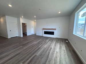 Spacious living area featuring wood-finish flooring, recessed lighting, and a modern built-in electric fireplace with a wood mantle
