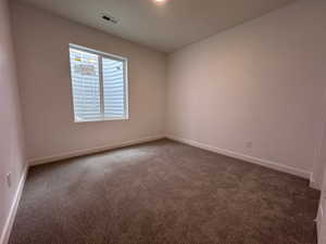 Spacious room featuring neutral carpet flooring, white walls, white trim, and a prominent window