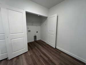 Laundry area featuring wood-finish flooring, white bi-fold doors, white interior walls, white baseboards, and a built-in wire shelf