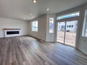 Spacious room featuring wood-finish flooring, a contemporary linear fireplace with a wood mantel, ample natural light from multiple windows, and recessed lighting