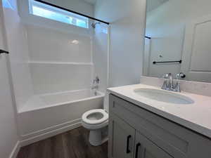 Bathroom featuring a white tub/shower combination with a transom window, a light gray vanity with black hardware, a light-colored countertop, and a vanity-mounted mirror